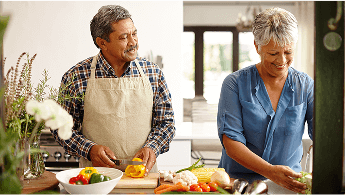Elderly man and woman chopping vegetables in a kitchen image