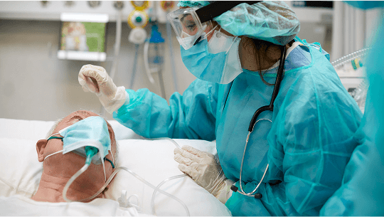 Elderly man wearing a mask in a hospital bed being examined by a healthcare professional wearing PPE image
