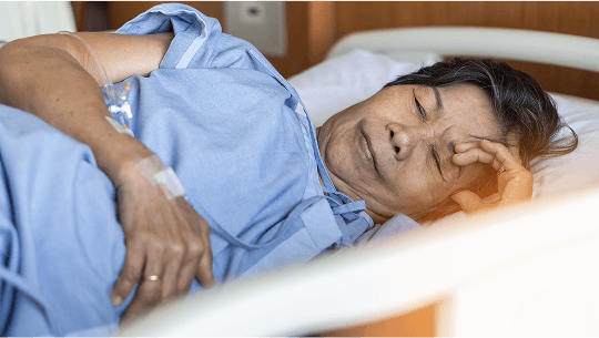 Elderly woman led on her side in a hospital bed with her eyes shut image