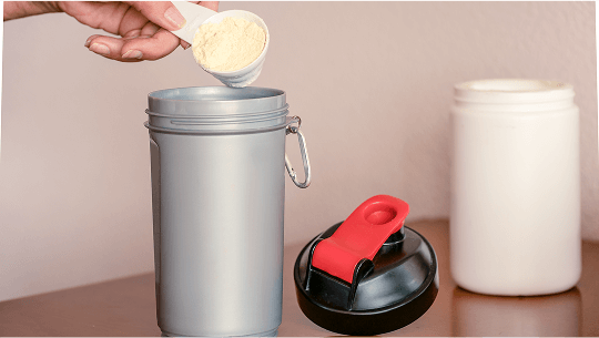 A scoop of powder being poured into a shaker image