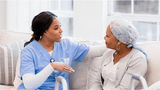 Healthcare professional sat on a sofa talking to a patient wearing a headscarf image