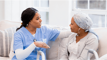 Healthcare professional sat on a sofa talking to a patient wearing a headscarf image
