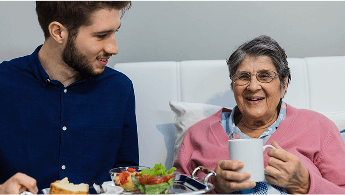 Man with serving tray of food for elderly lady sat down image
