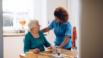 Carer serving an elderly woman in her home a plate of food image