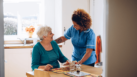 Carer serving an elderly woman in her home a plate of food image