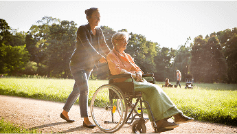 Elderly lady outside in a wheelchair being pushed by a younger lady image