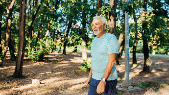 Elderly man outside walking near trees image