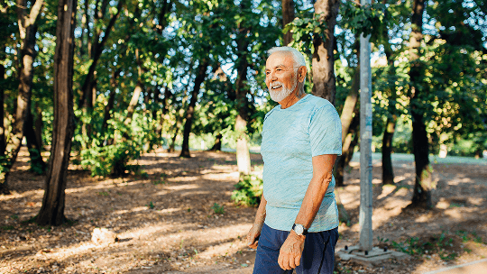 Elderly man outside walking near trees image