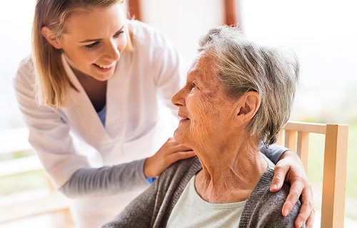Elderly lady sat down being comforted by a healthcare professional image
