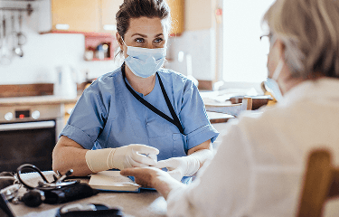 Helathcare professional wearing a facemask, examining a female patient's hand image