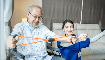 Elderly man doing band exercises using his arms whilst sat in a wheelchair image