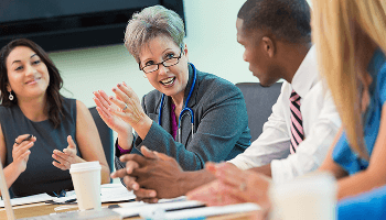 People sat around a table clapping image