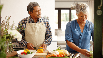 Elderly man and woman chopping vegetables in a kitchen image