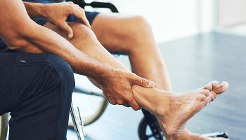 Person in a wheelchair having their leg held and examined by another person image