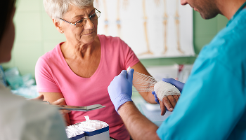 Elderly woman having her hand bandaged up by a healthcare professional image 