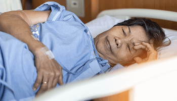 Elderly woman led on her side in a hospital bed with her eyes shut image