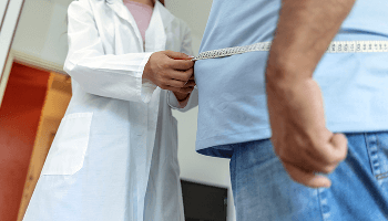 Healthcare professional measuring the waist of an overweight man image