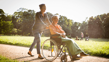 Elderly lady outside in a wheelchair being pushed by a younger lady image