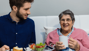 Man with serving tray of food for elderly lady sat down image