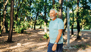 Elderly man outside walking near trees image