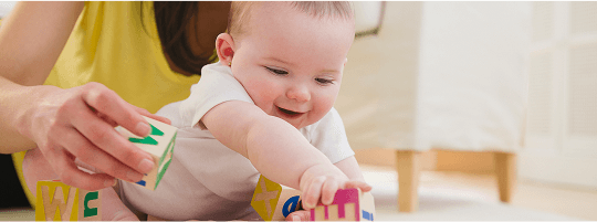 Baby with a woman on the floor, playing with wooden blocks together image