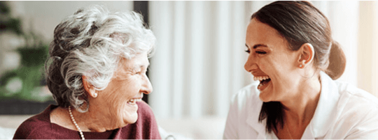 Elderly lady and young lady looking at eachother laughing image