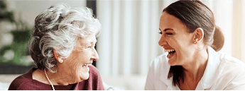 Elderly lady and young lady looking at eachother laughing image