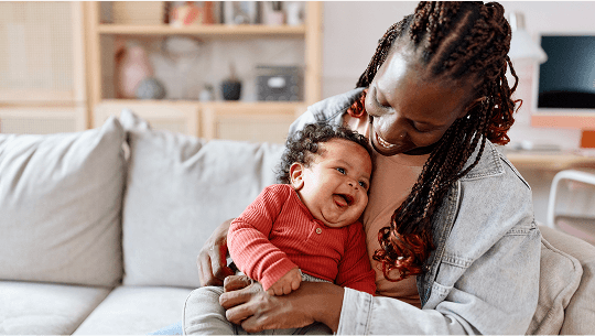 Baby laughing whilst in the lap of a woman image