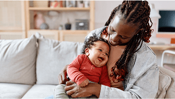 Baby laughing whilst in the lap of a woman image