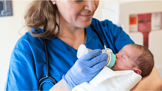 Healthcare professional holding and feeding a baby image