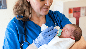 Healthcare professional holding and feeding a baby image
