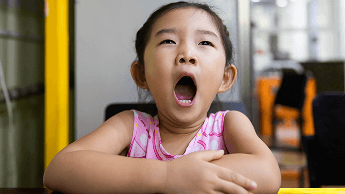 Child sat at a table and yawning image