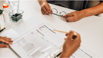 Person filing out a dietary assessment form on a desk image