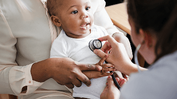 Baby being held by a woman whilst a doctor examines the baby using a stethoscope image