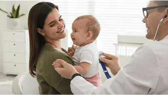 Baby being held by a woman whilst a doctor examines the baby using a stethoscope image