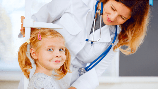 Child smiling whilst having her height measured by a healthcare professional image