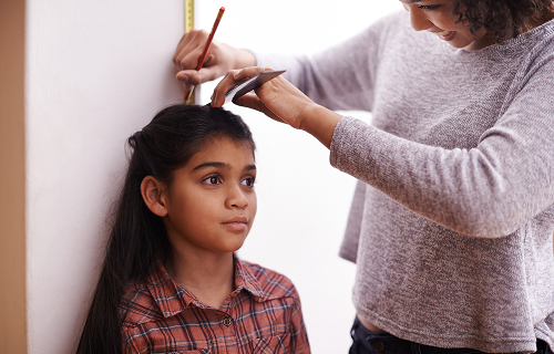 Child being measured against a wall by a woman image