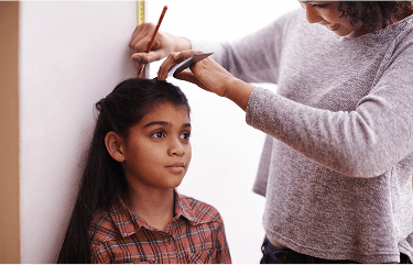 Child being measured against a wall by a woman image