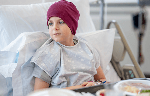 Child waering a head scarf in a hospital bed image