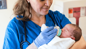 Healthcare professional holding and feeding a baby image