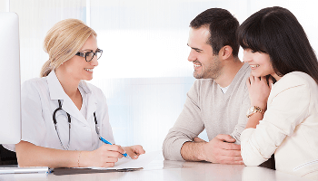 Healthcare professional having a conversation with a young couple at a desk image