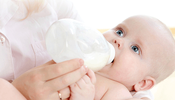 Baby being fed using a baby bottle image