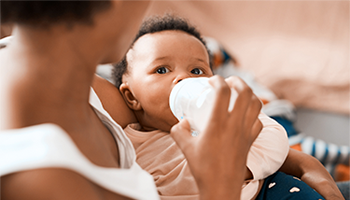 Baby being fed using a baby bottle image