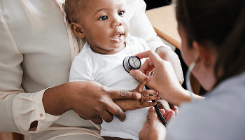 Baby being held by a woman whilst a doctor examines the baby using a stethoscope image