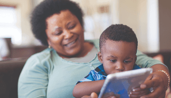 Child using a tablet device whilst sat on a woman's lap image