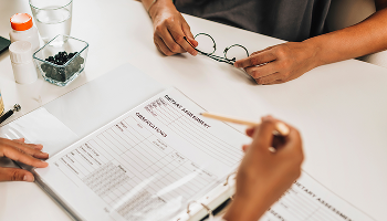 Person filing out a dietary assessment form on a desk image