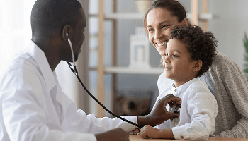 Child sat on a woman's lap, being examined by a healthcare professional using a stethoscope image