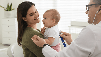 Baby being held by a woman whilst a doctor examines the baby using a stethoscope image