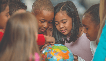 Children gathered around and examining a globe of the world image