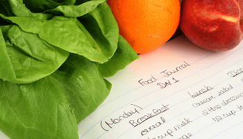 Notepad with food diary information within it, next to healthy foods image